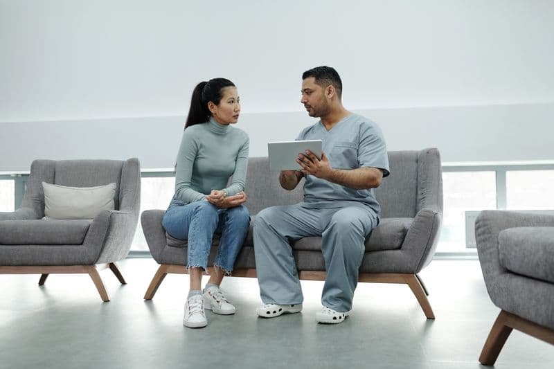 A clinician and a patient talking together in a clinic waiting area.